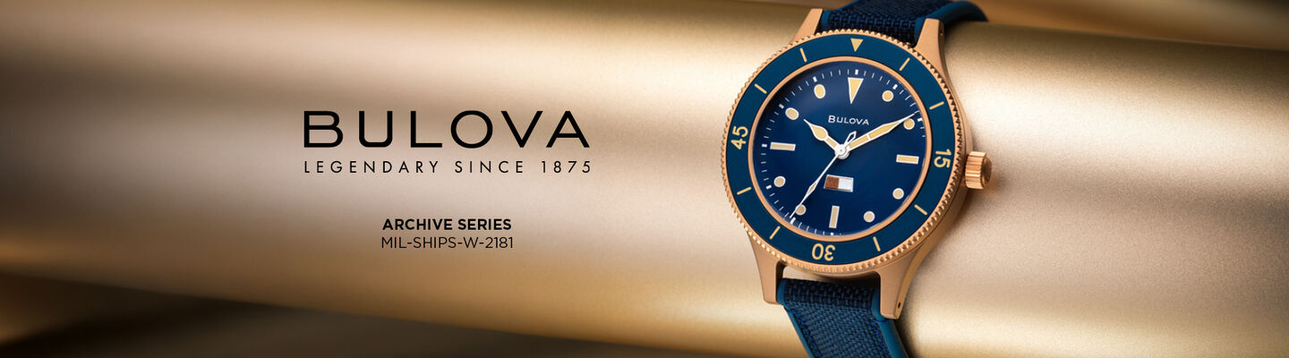 Bulova Archive Series MIL-SHIPS-W-2181 gold-tone automatic watch with blue dial and NATO strap on gold background.